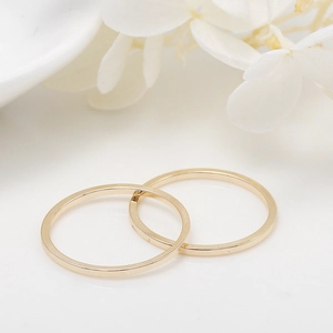 Minimalist pair of golden copper open rings with a polished linear finish on white background
