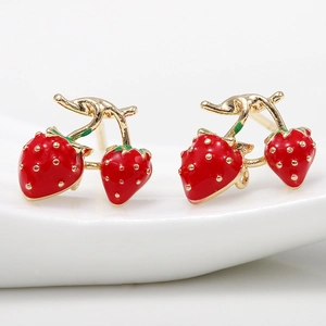 Detail of red and gold strawberry stud earrings with green leaves on ceramic base