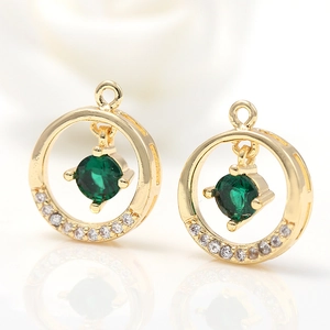 Detail of 14k gold plated round pendant with green gemstone and small white crystals