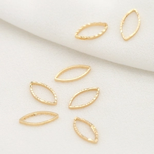 Detailed view of golden marquise-shaped metal jewelry DIY components on white fabric