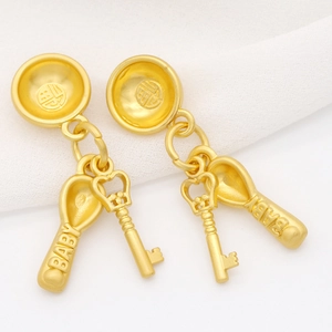 Macro shot of gold-plated baby charms with Fu character and engraved spoon and key pendants