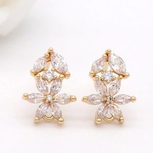 Boucles d'oreilles fleurs dorées avec zircons marquise sur un fond blanc épuré