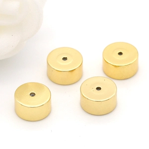 Detailed view of four polished gold cylindrical metal beads for DIY jewelry making
