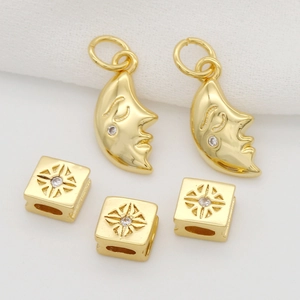 Macro shot of gold-plated crescent moon pendants and square geometric star beads on white fabric