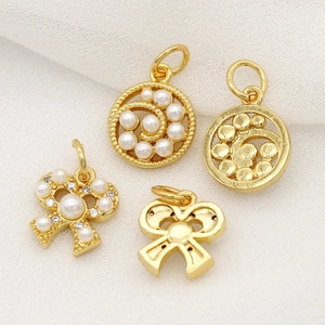 Detail of 14k gold plated copper swirl and bow charms with rainbow zircon and pearls