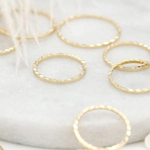 Gepolijste 14K vergulde getextureerde ringen op een wit marmeren plateau getoond
