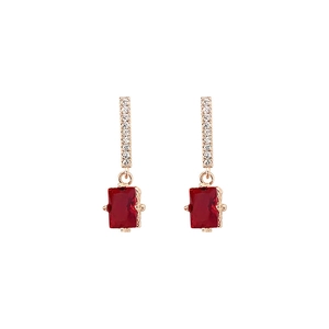 Macro shot of rose gold earrings featuring micro-paved zircons and a ruby red rectangular stone