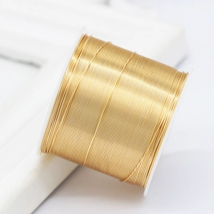 Bright gold copper craft wire for DIY jewelry making neatly wound on a plastic spool