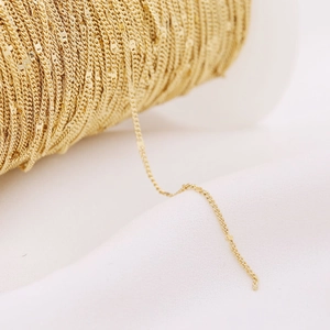 Close-up of shiny gold-plated jewelry chain on a white spool for DIY jewelry making