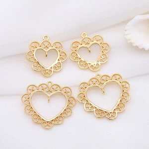 Lace-edged gold heart charms for DIY jewelry making displayed on a textured fabric
