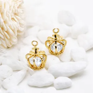 Detalle de colgantes de corona bañados en oro 14K con circonitas sobre piedras