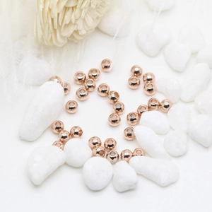 Macro shot of polished rose gold metal spacer beads for DIY jewelry making on white background