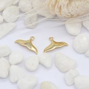 Detail van 14K vergulde dolfijnstaart hangers met ronde ringen op witte kiezelstenen