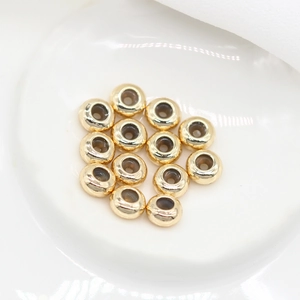 Nahaufnahme von 14K vergoldeten Stopper-Perlen für DIY-Schmuck auf weißem Keramik
