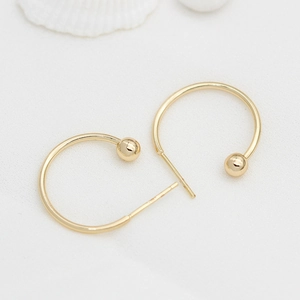 Aros grandes minimalistas chapados en oro de 14K con cuenta sobre textura blanca