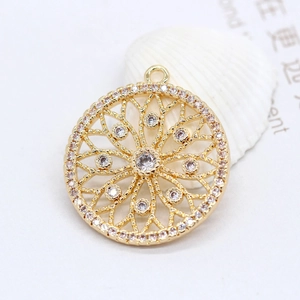 Detail of a 14k gold plated round charm with radiating geometric patterns and zircon stones