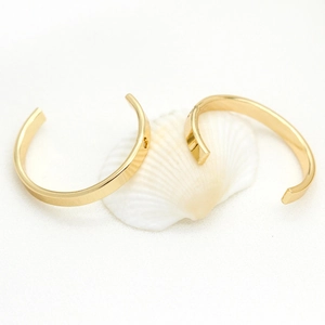 Pampilles d'oreilles en laiton plaqué or 14K en forme de C sur un coquillage blanc