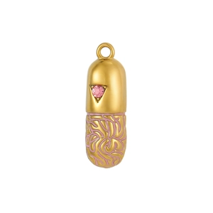 Detailed macro view of a gold capsule pendant with pink gemstone and maze-like patterns