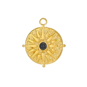 Detail of a golden sunburst pendant with a black gemstone and hammered texture