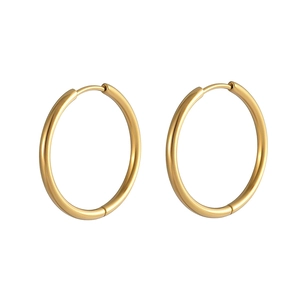 Macro detail of polished gold hoop earrings featuring minimalist design and clasp closure