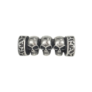 Close-up of vintage steel bead with three skulls and engraved tribal patterns