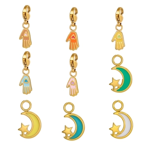 Detail of colorful enamel Hamsa hand and crescent moon charms with gold lobster clasps
