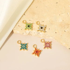 Dettaglio macro di cinque mini ciondoli a stella con zirconi colorati e placcati oro