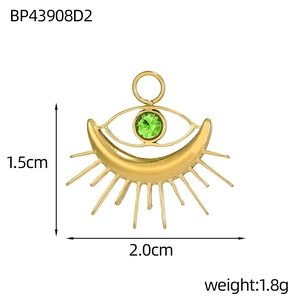 Detailed view of tarot-style gold heart pendant with green gem, moon and eye motif