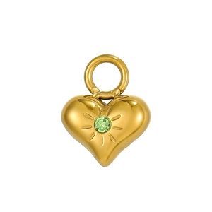 Dettaglio del ciondolo a cuore dorato con zircone verde e incisione a raggiera