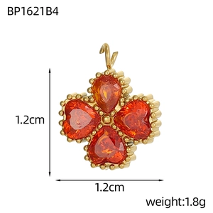 Dettaglio del ciondolo a quadrifoglio dorato con pietre rosse, 1,2 cm e peso di 1,8 g