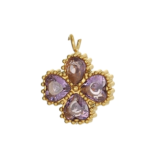Dettaglio di un ciondolo a quadrifoglio dorato con cristalli viola a cuore
