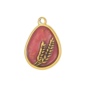 Detailed macro view of a gold teardrop pendant with red enamel and wheat ear motifs