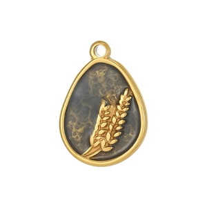 Macro view of teardrop pendant with golden wheat ear pattern and vintage texture