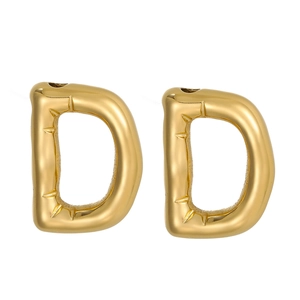 Macro detail of golden 14k D-letter pendant with irregular lava texture and inner spikes