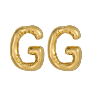 Detail of gold balloon style letter G stud earrings with realistic puffy metallic texture