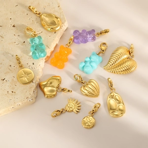 Colgantes de oso y corazón en acero dorado sobre piedra beige para joyas DIY