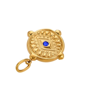 Macro detail of a golden evil eye pendant with blue zircon and sunburst engravings