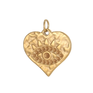 Detalle de un colgante de corazón dorado vintage con relieve de ojo turco y textura de metal martillado