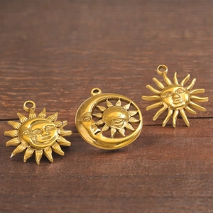 Detail view of vintage sun and moon charms for DIY jewelry on rustic wood surface