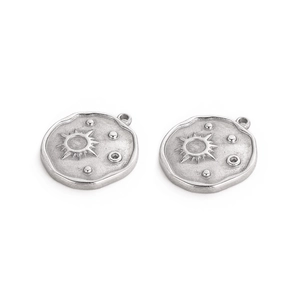 Macro detail of hand-hammered silver sun and star moon pendant charms for DIY jewelry