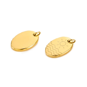 Detailed macro view of gold plated stainless steel oval pendants with sun engraving