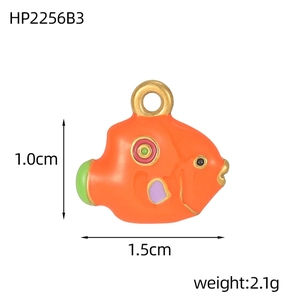 Macro detail of orange enamel fish charm with colorful accents and golden loop