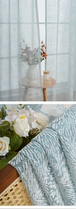 Detailed weave of light blue sheer curtain with white starburst jacquard patterns