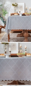 Close-up of light gray tablecloth with white clover pattern and scalloped lace edges