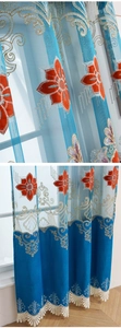 Detailed close-up of blue European sheer curtain with red floral embroidery and lace trim