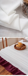 Detailed macro view of white linen texture tablecloth with wine red ruffled edge design