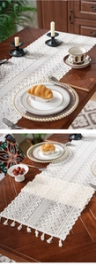 Detail of hollow crochet table runner with fringe tassels in rustic French vintage style