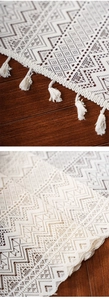 Detail view of cream crochet table runner with geometric lace patterns and tassel edges