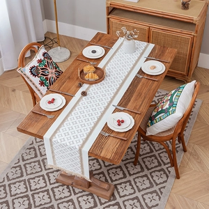 Bohemian geometric table runner with tassels on a wooden dining table in a cozy home setting