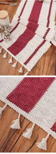 Macro detail of red and beige striped woven table runner with decorative white fringe